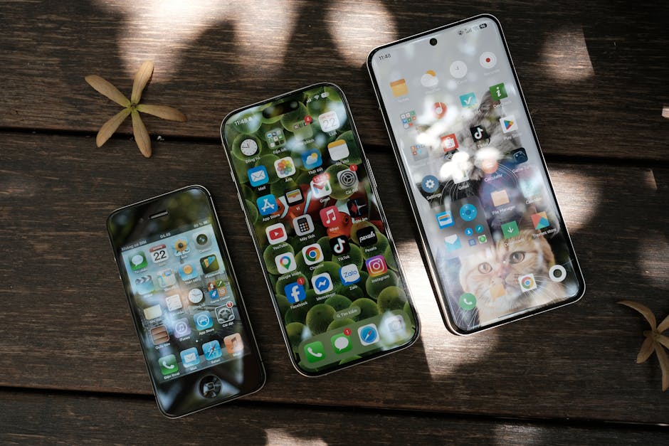 A collection of smartphones showing different app icons, placed on a wooden surface in natural light.